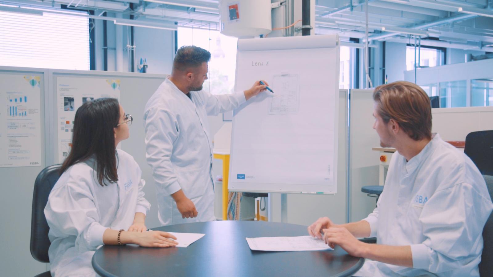 Ausbildner in einer Besprechung mit auszubildenden Feinwerkoptikern