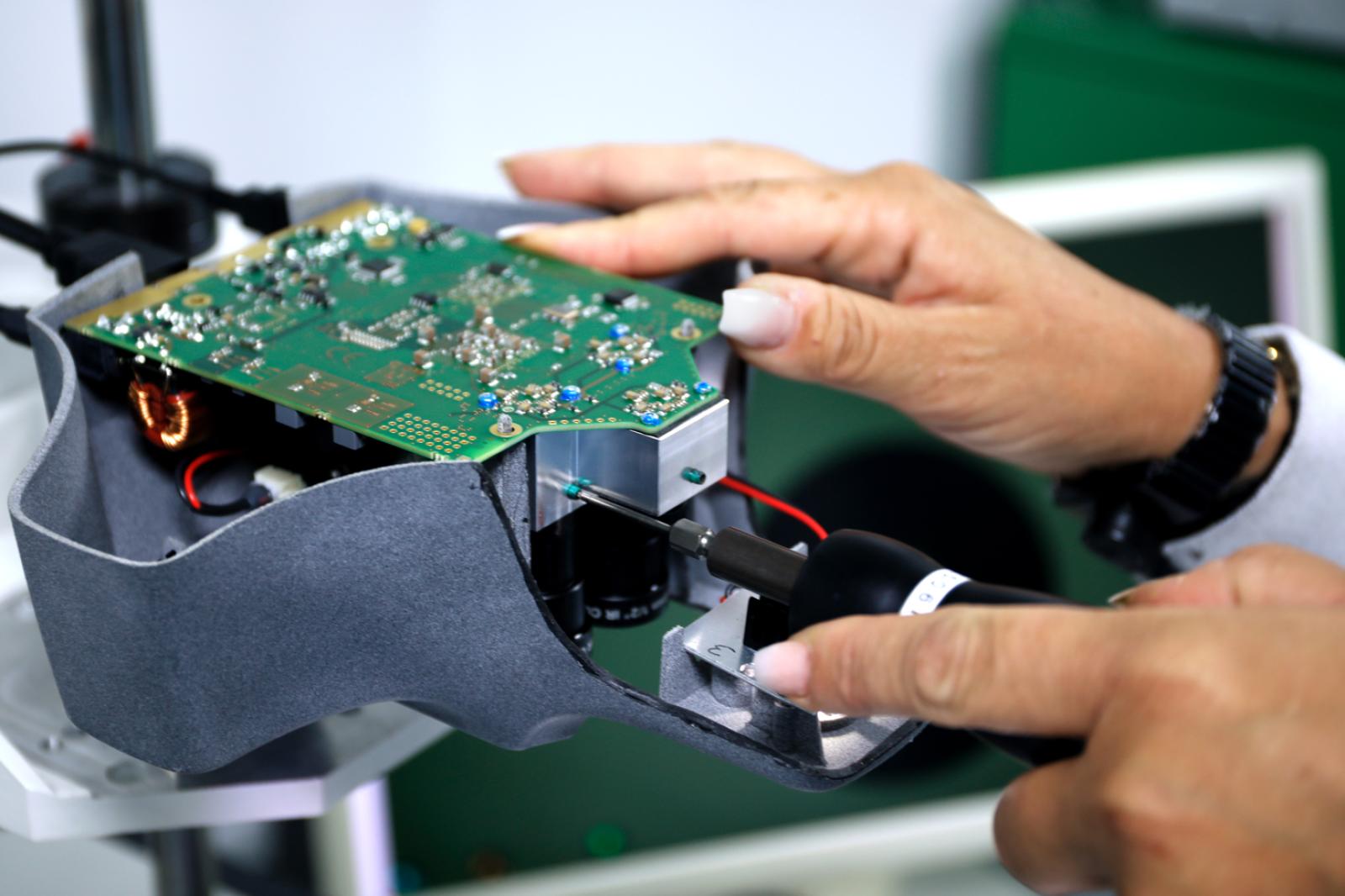 FISBA Mitarbeiterin schraubt geerdet das Metall-Gehäuse um die vorab verarbeitete Elektronik zu